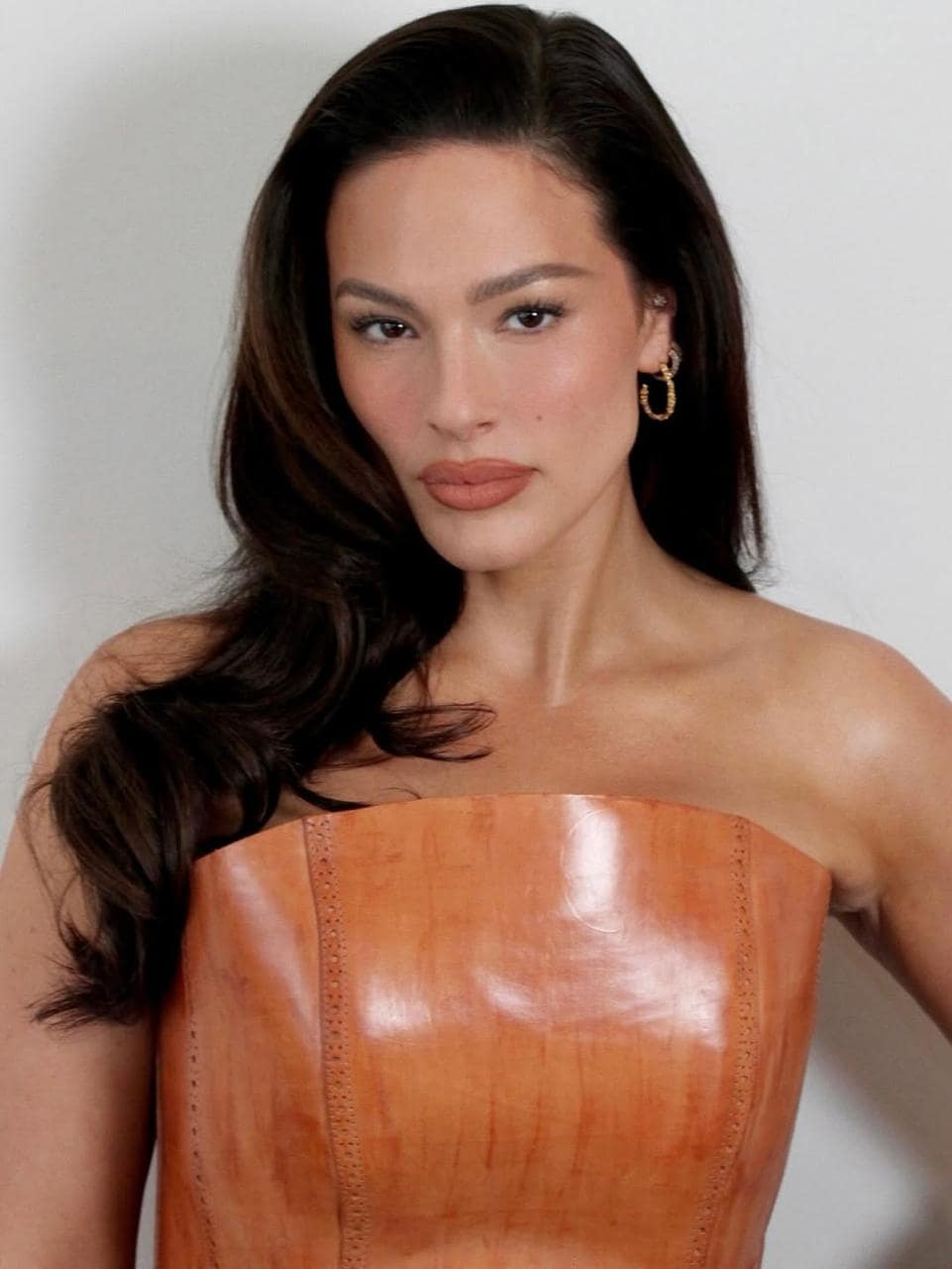 Ashley Graham wearing a monochromatic terracotta makeup look with warm earth tones and a structured leather top 2026 beauty trend.